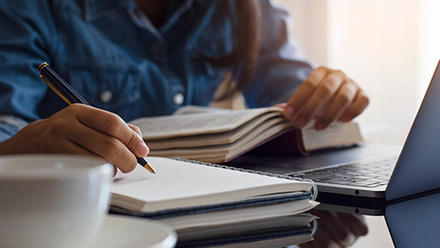 Student handwriting information on diary notebook while reading book shutterstock_1700556118r.jpg